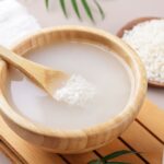 Homemade cosmetic rice water with ingredients on beige background