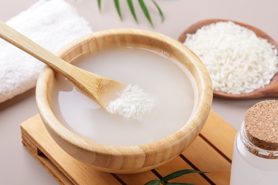 Homemade cosmetic rice water with ingredients on beige background